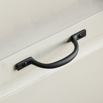 Black d shaped handle screwed to an off white cupboard door