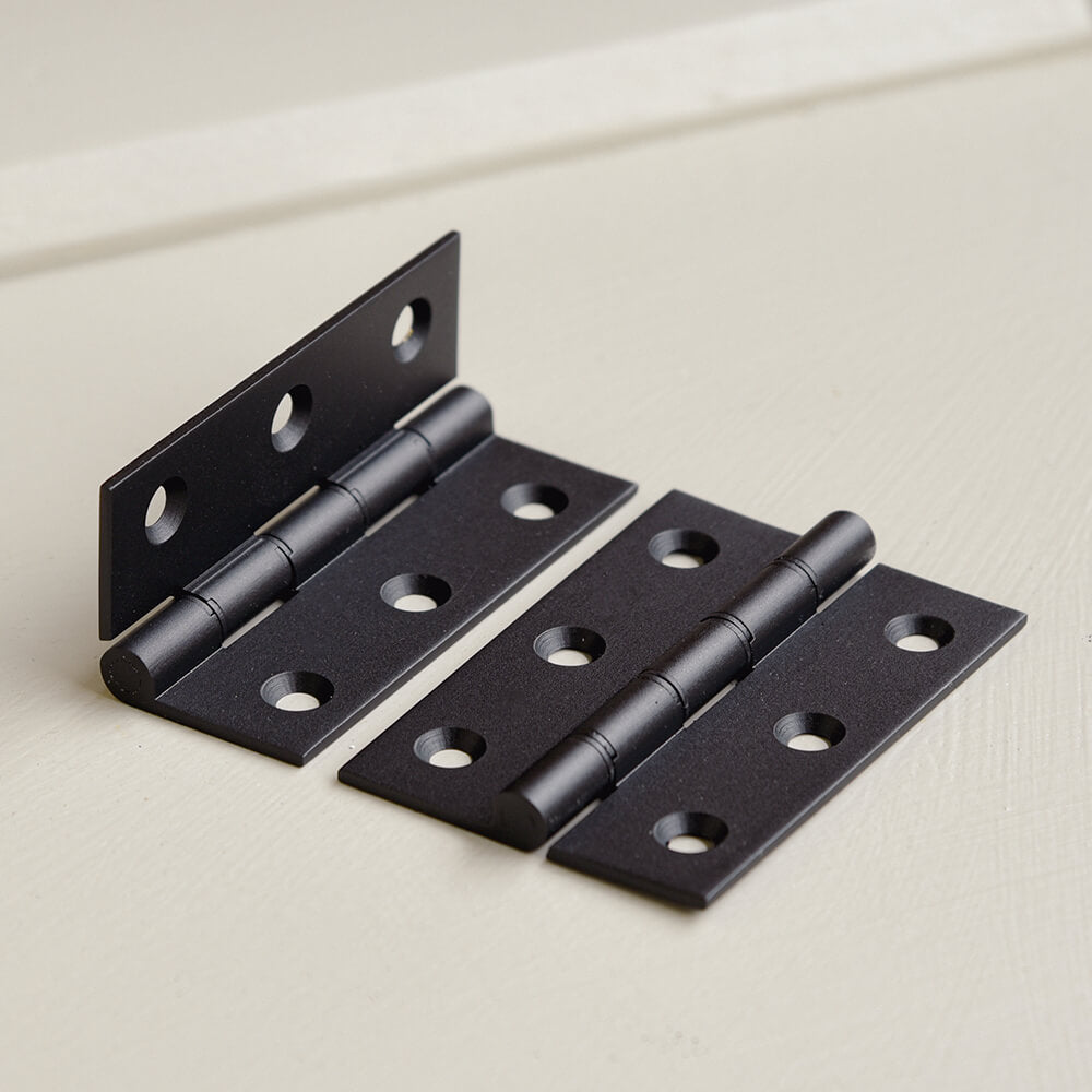 Set of black metal hinges on a light background