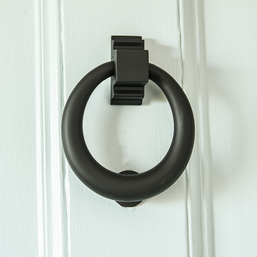 Smooth matt black circular hoop ring door knocker on pale blue door