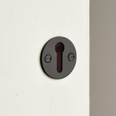 Matte black door escutcheon without a cover on an off-white painted door