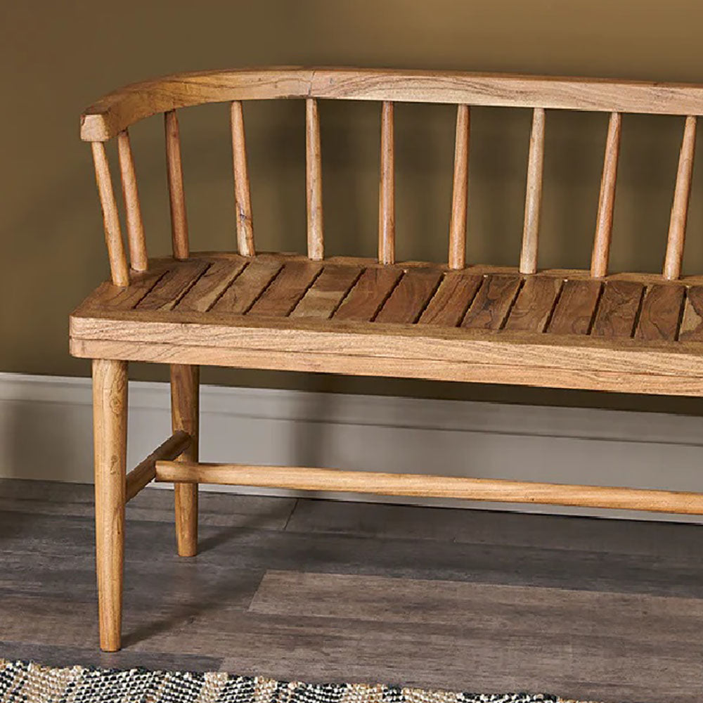 Acacia wood bench with curved backrest and tapered legs against olive green wall