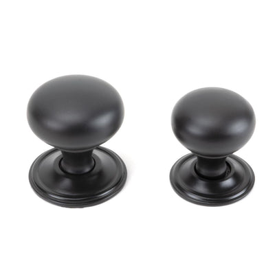 Small and large age bronze cabinet knobs against a white background