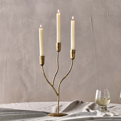 3 arm antique brass candelabra on a grey tablecloth against a grey wall