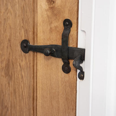 Black beeswax door latch fitted to a wooden door with a white door frame