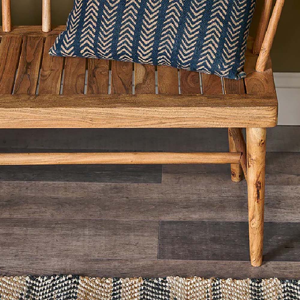 Close up of acacia wooden bench with tapered legs and blue and white striped cushion placed o top