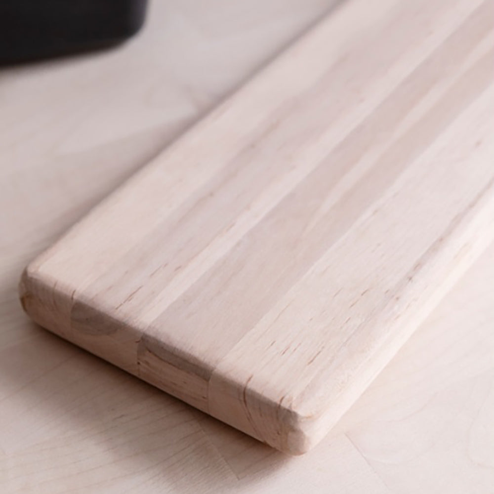 Close up of a alderwood long serving board sat on a wooden worktop