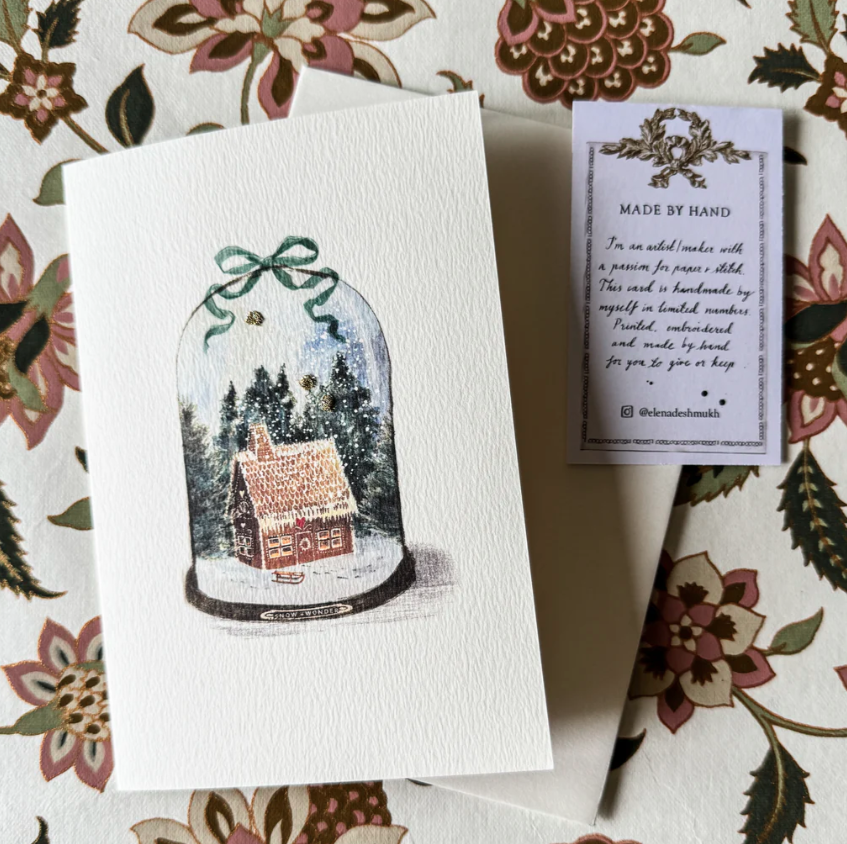 Card with a snowglobe design featuring a house on a floral-patterned background