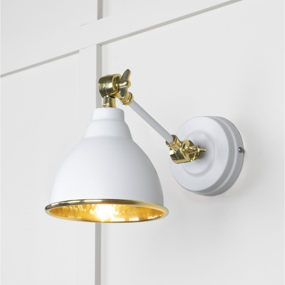 Hammered brass Brindley wall light in white against a white panelled wall