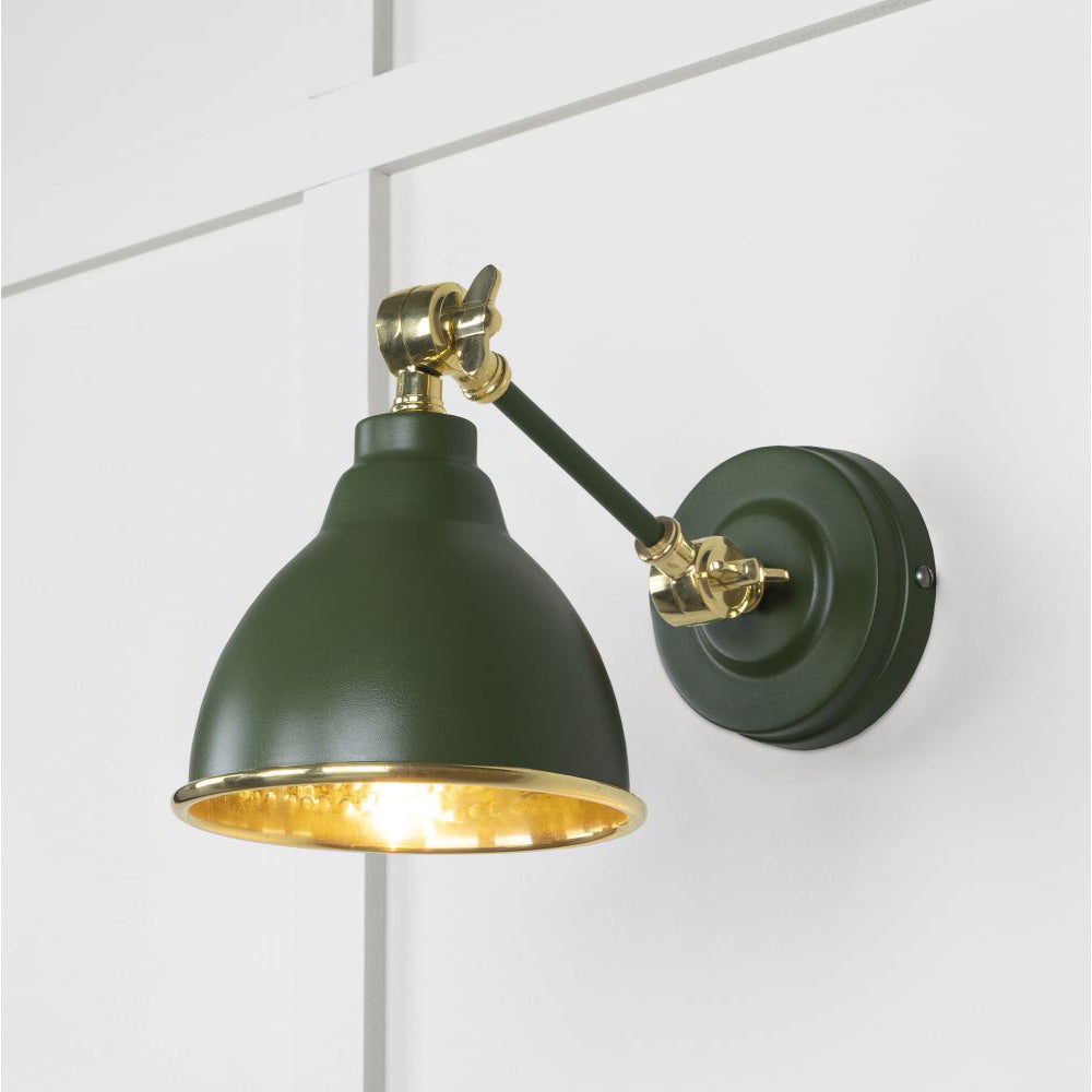 Hammered brass Brindley wall light in green against a white panelled wall