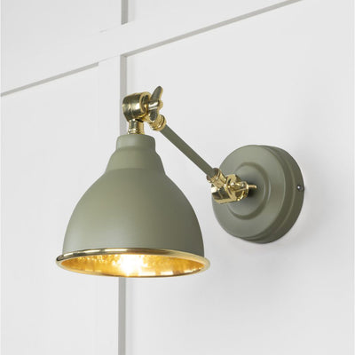 Hammered brass Brindley wall light in light green against a white panelled wall
