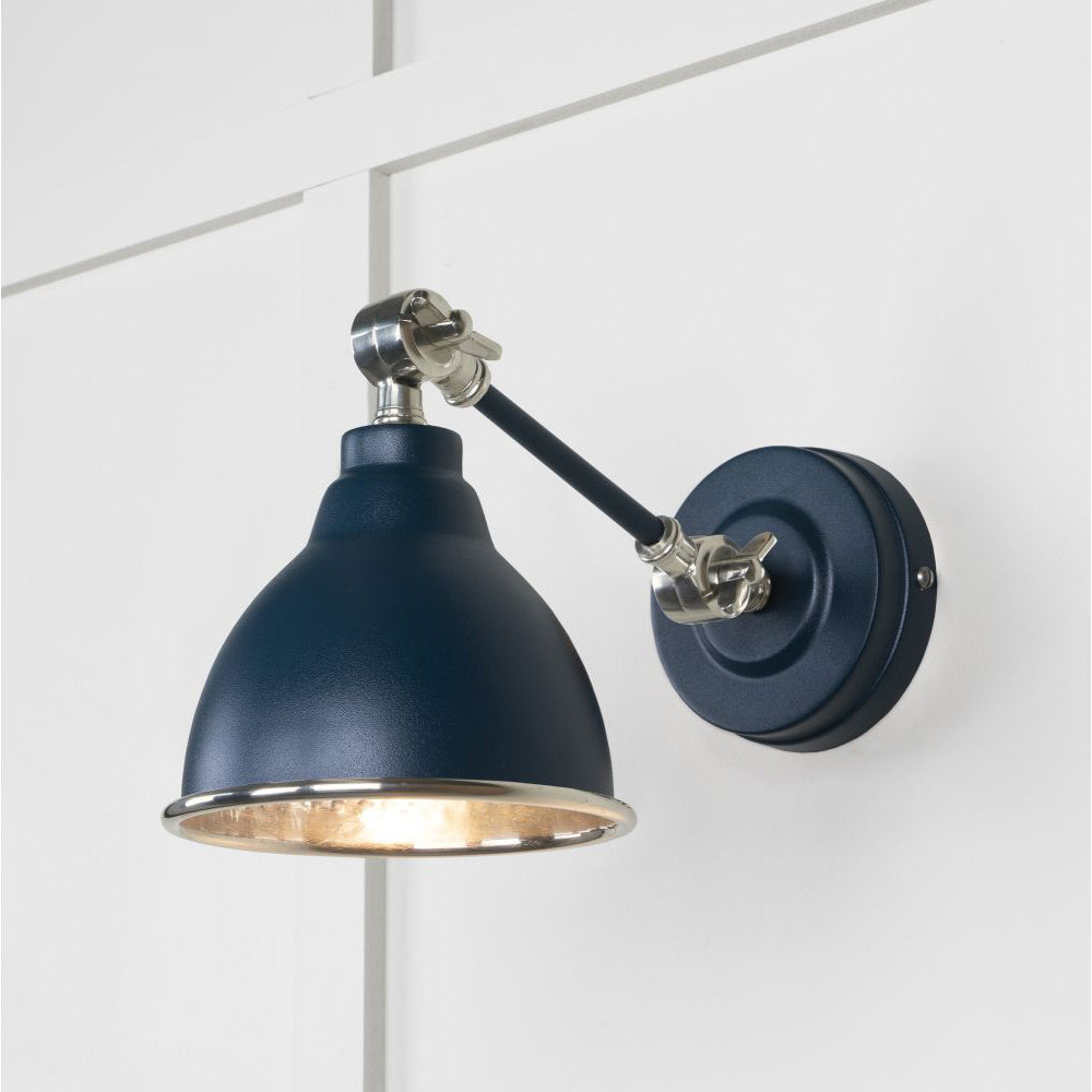 Hammered nickel Brindley wall light in navy against a white panelled wall