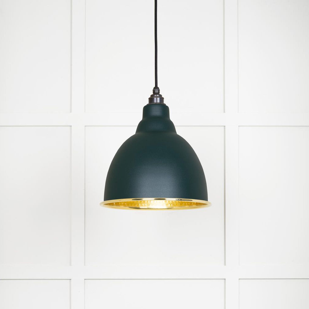 Hammered polished brass Brindley pendant light in dingle hanging from a black fabric cord against a white panelled wall