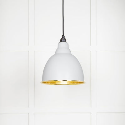 Hammered polished brass Brindley pendant light in flock hanging from a black fabric cord against a white panelled wall