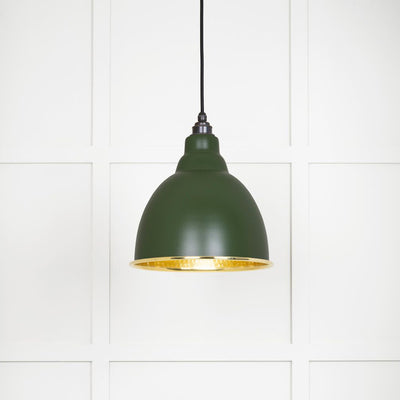 Hammered polished brass Brindley pendant light in heath hanging from a black fabric cord against a white panelled wall