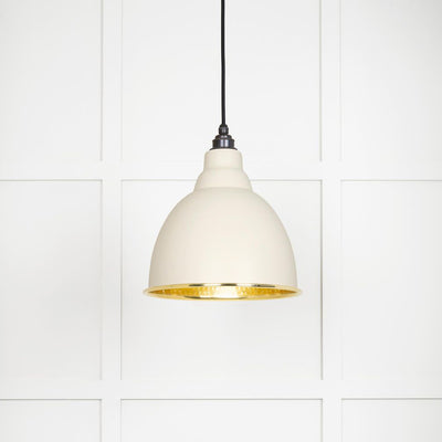 Hammered polished brass Brindley pendant light in teasel hanging from a black fabric cord against a white panelled wall