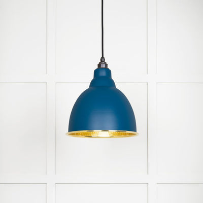 Hammered polished brass Brindley pendant light in upstream hanging from a black fabric cord against a white panelled wall