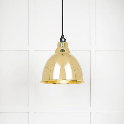 Hammered brass Brindley wall light hung from black fabric cable against a white panelled wall