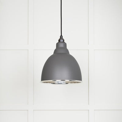 Hammered polished nickel Brindley pendant light in bluff hanging from a black fabric cable against a white panelled wall