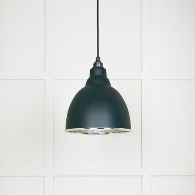 Hammered polished nickel Brindley pendant light in dingle hanging from a black fabric cable against a white panelled wall