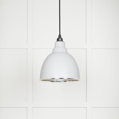 Hammered polished nickel Brindley pendant light in flock hanging from a black fabric cable against a white panelled wall
