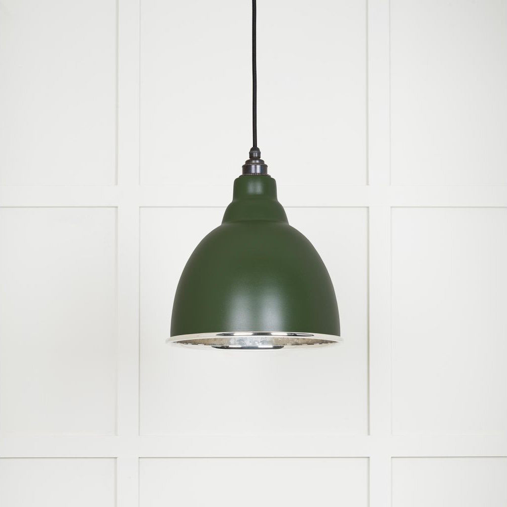 Hammered polished nickel Brindley pendant light in heath hanging from a black fabric cable against a white panelled wall