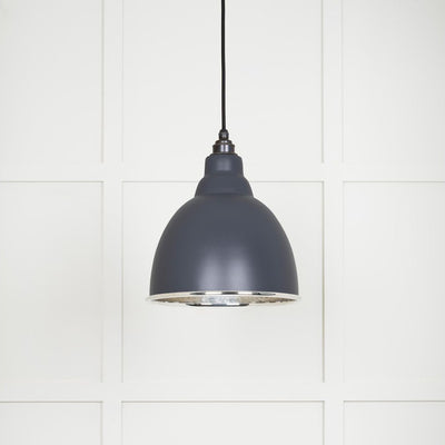 Hammered polished nickel Brindley pendant light in slate hanging from a black fabric cable against a white panelled wall
