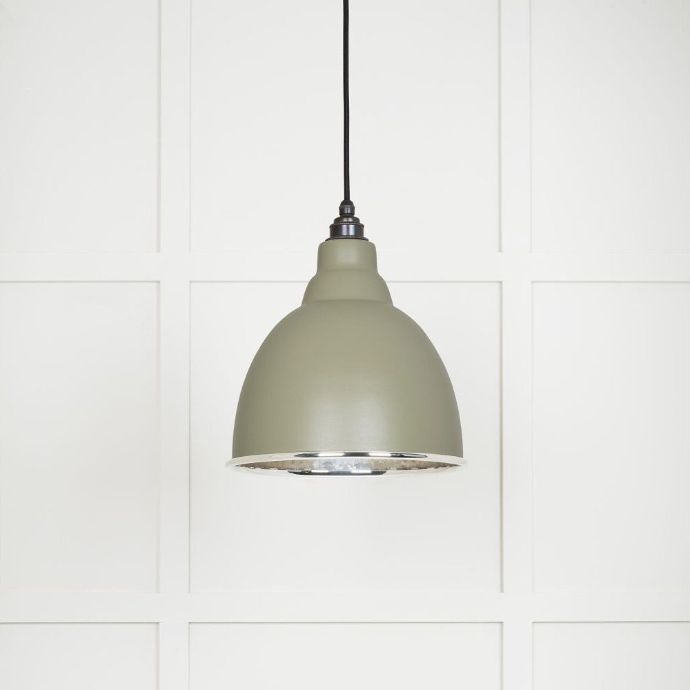 Hammered polished nickel Brindley pendant light in tump hanging from a black fabric cable against a white panelled wall