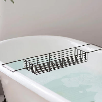 Iron wire bath caddy with an antique brass finish resting on an enamel bath filled with water