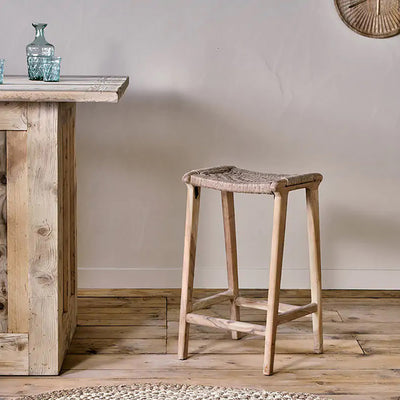 Mango wood and jute counter stool stood on a wooden floor next to a wooden kitchen counter and white wall