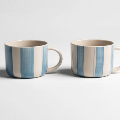 Two striped ceramic mugs on a light gray background