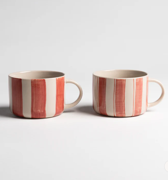 Two striped ceramic mugs on a light gray background
