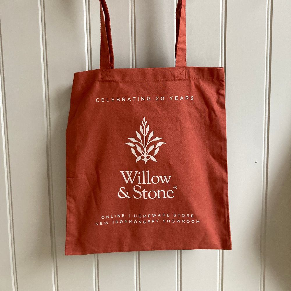 Burnt orange tote bag with 'Willow & Stone' branding on a white wooden background