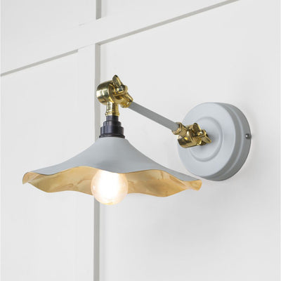 Smooth brass flora wall light in birch against a white panelled wall