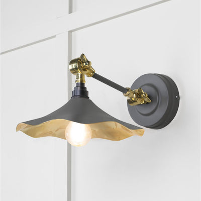 Smooth brass flora wall light in bluff against a white panelled wall