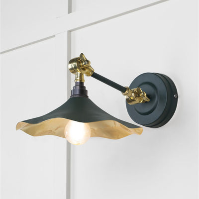 Smooth brass flora wall light in dingle against a white panelled wall