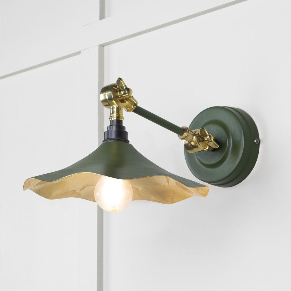 Smooth brass flora wall light in heath against a white panelled wall