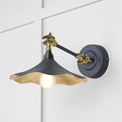 Smooth brass flora wall light in slate against a white panelled wall