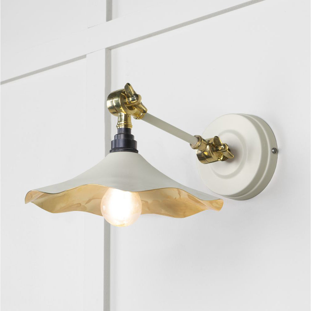 Smooth brass flora wall light in teasel against a white panelled wall