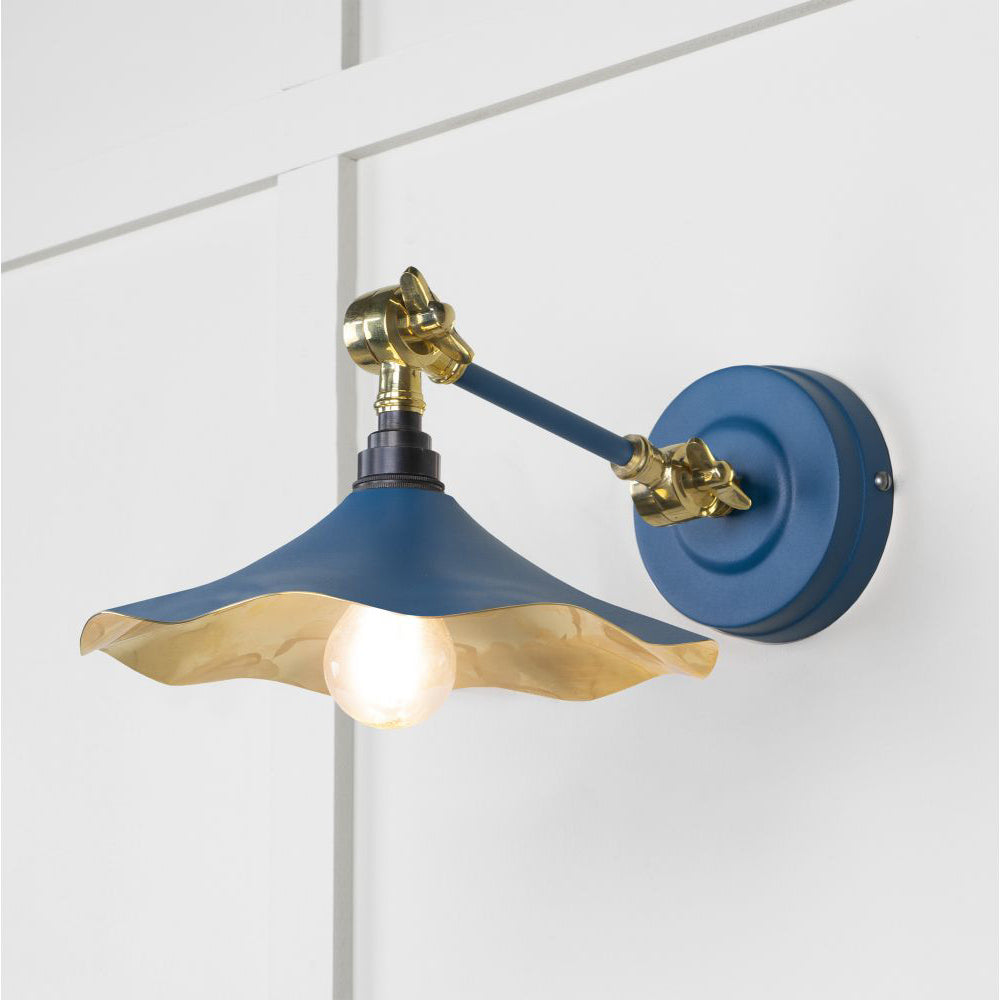 Smooth brass flora wall light in upstream against a white panelled wall