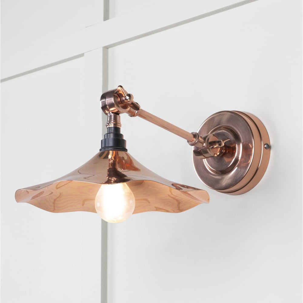 Smooth copper flora wall light against a white panelled wall