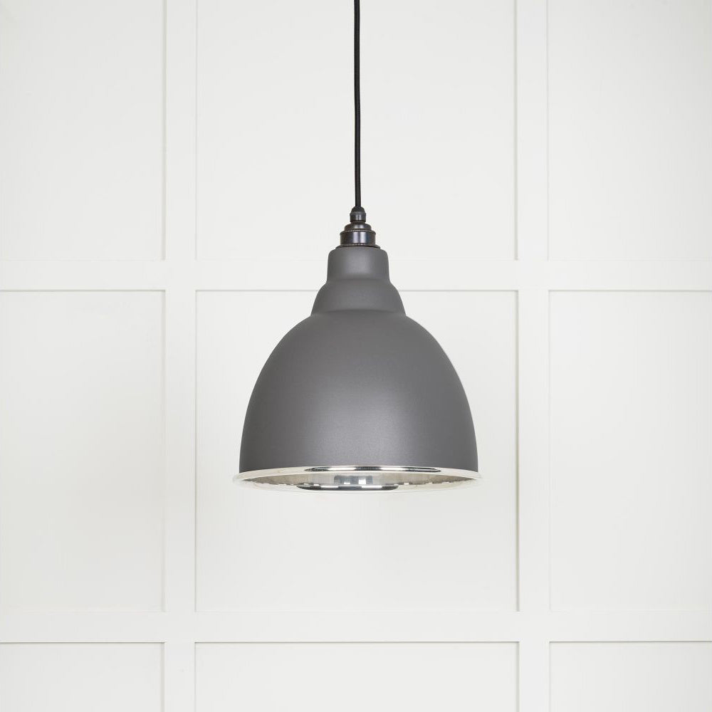Smooth polished nickel Brindley pendant light with a powder coated finish in bluff hanging from a black fabric cable against a white panelled wall