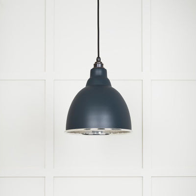 Smooth polished nickel Brindley pendant light with a powder coated finish in soot hanging from a black fabric cable against a white panelled wall