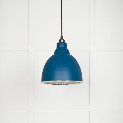 Smooth polished nickel Brindley pendant light with a powder coated finish in upstream hanging from a black fabric cable against a white panelled wall