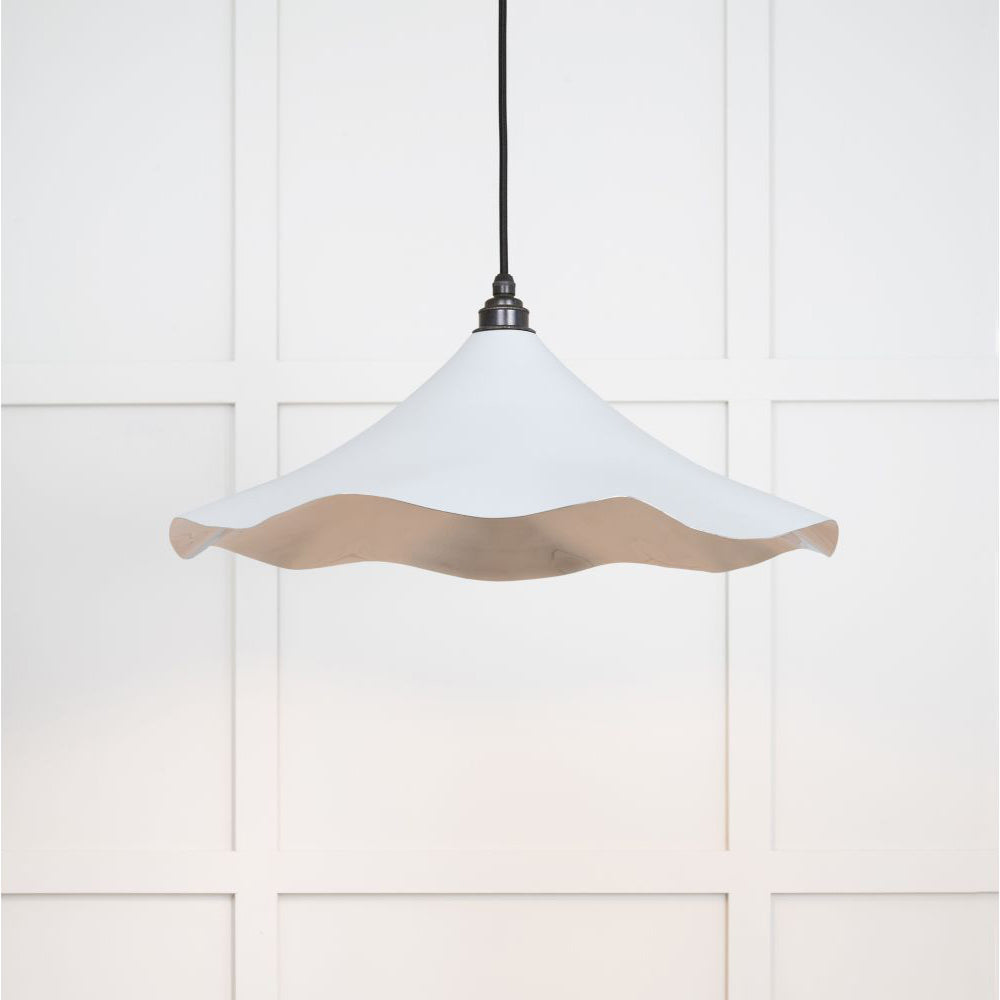 Smooth nickel flora pendant light in birch hanging from a black fabric cord against a white panelled wall