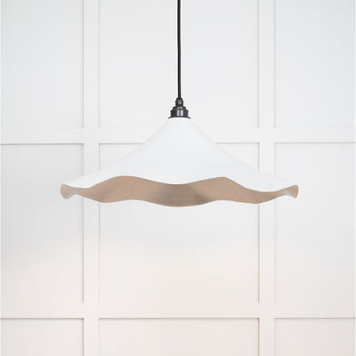 Smooth nickel flora pendant light in flock hanging from a black fabric cord against a white panelled wal