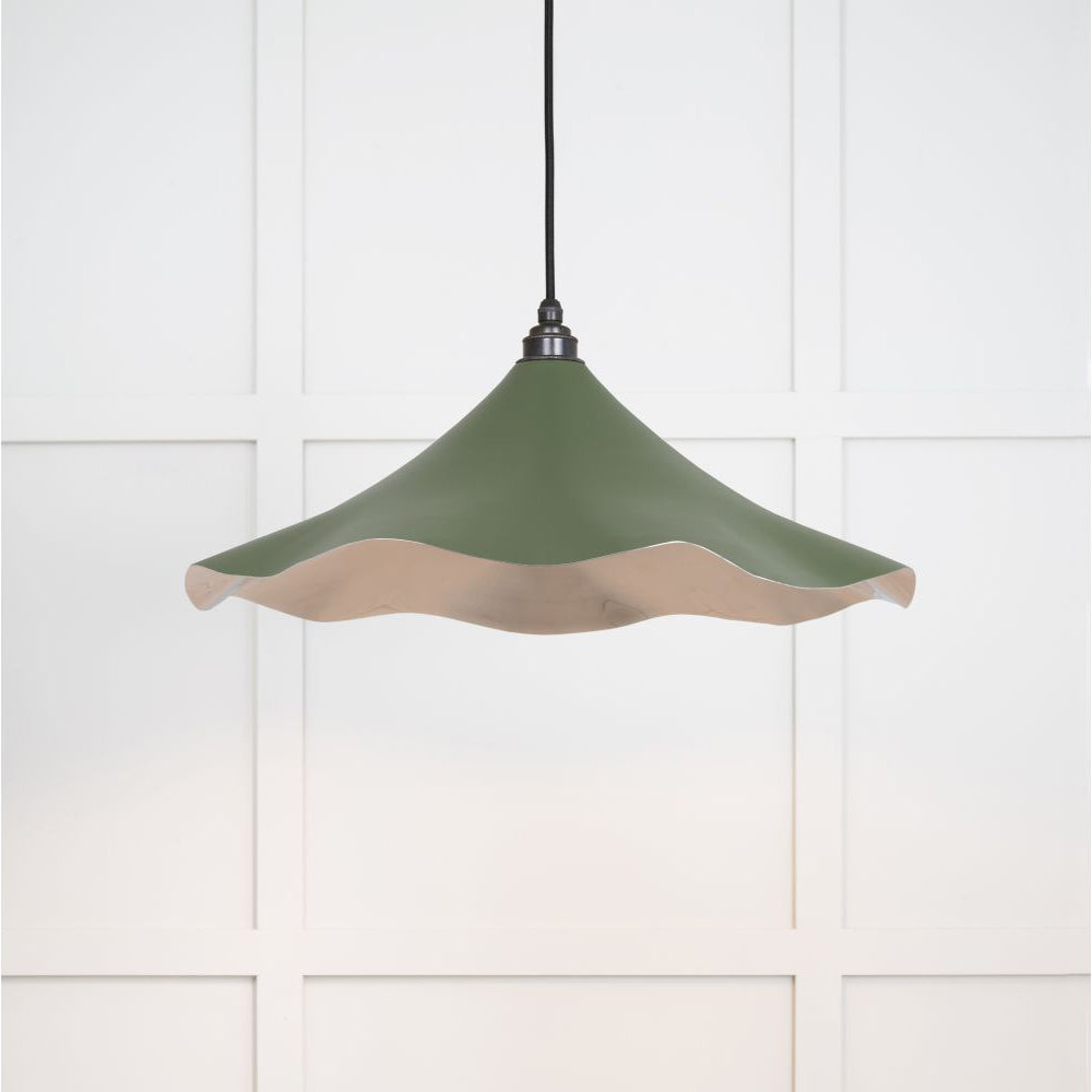 Smooth nickel flora pendant light in heath hanging from a black fabric cord against a white panelled wal