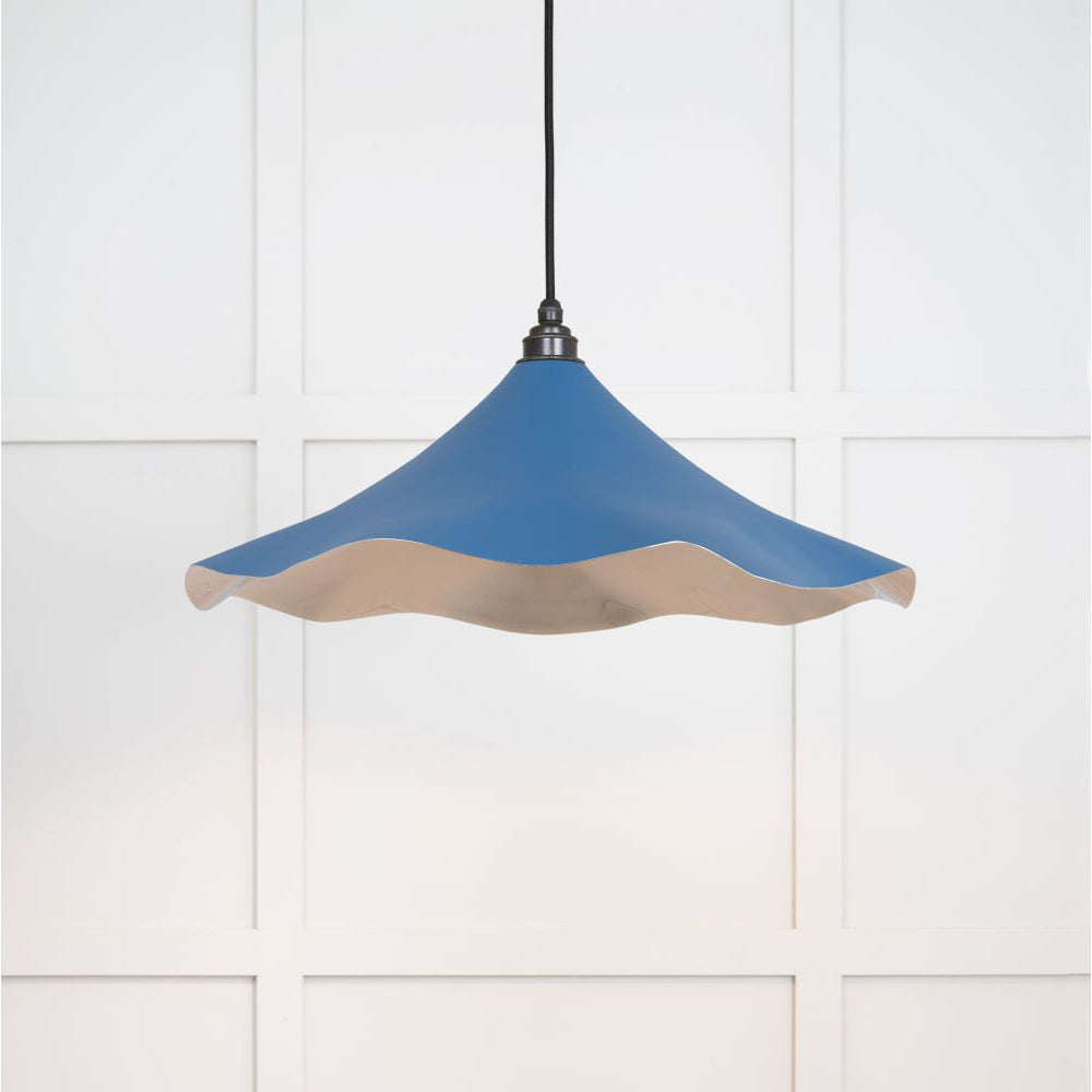 Smooth nickel flora pendant light in upstream hanging from a black fabric cord against a white panelled wal
