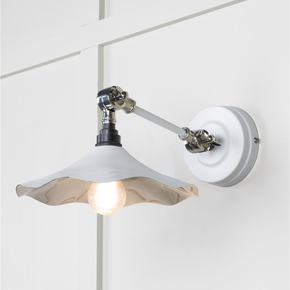 Smooth polished nickel flora wall light in flock against a white panelled wall