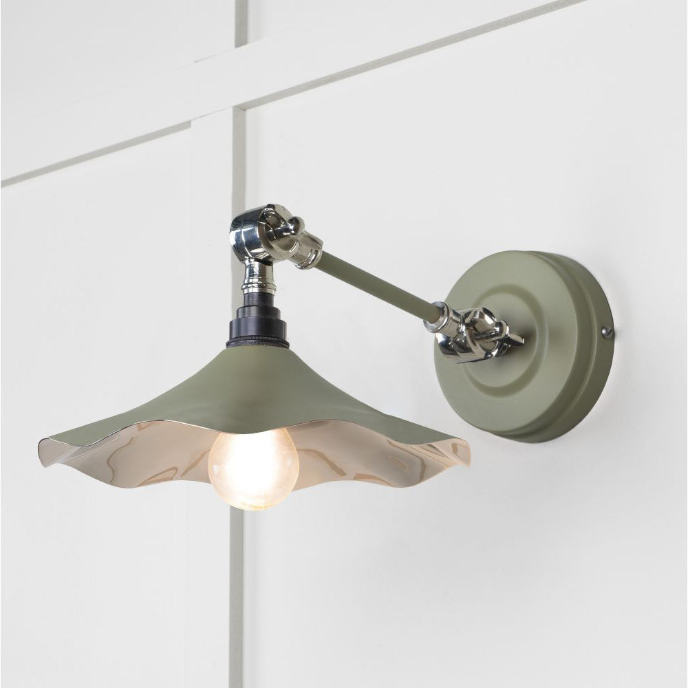 Smooth polished nickel flora wall light in tump against a white panelled wall