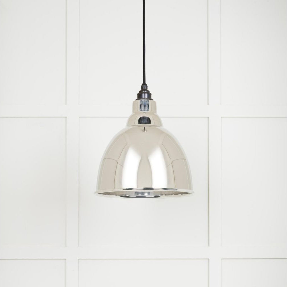 Smooth polished nickel Brindley pendant light hanging from a black fabric cord against a white panelled wall